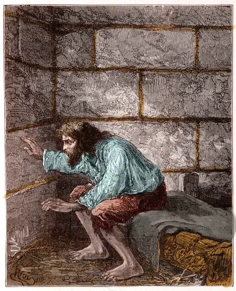 Prisoner reaching through the bars of a stone cell